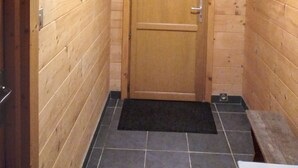 A wooden interior hallway with a door, a bench, and a tiled floor. - Eco-friendly house in the French countryside (Donzy)