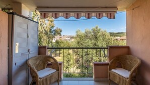 Varanda com duas cadeiras de vime e vista para uma área residencial.