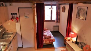 A compact room with a kitchenette, a bed, and a small table with a lamp. - Cozy duplex 33m² in Arêches-Beaufort, 4 pers., ski-in/ski-out, pets allowed, parking (Arêches-Beaufort)