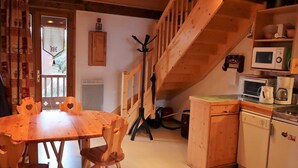 A cozy kitchen with wooden furniture, a dining table, and a staircase leading to an upper level. - Cozy duplex 33m² in Arêches-Beaufort, 4 pers., ski-in/ski-out, pets allowed, parking (Arêches-Beaufort)