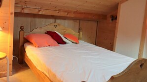 A wooden bed in a cabin-style room with a simple headboard and a small bedside table. - Cozy duplex 33m² in Arêches-Beaufort, 4 pers., ski-in/ski-out, pets allowed, parking (Arêches-Beaufort)