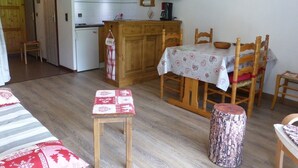 A cozy kitchen with wooden cabinets, a microwave, and a dining area with a table and chairs.