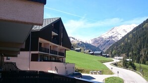 A building with a balcony overlooking a road and a mountainous landscape.