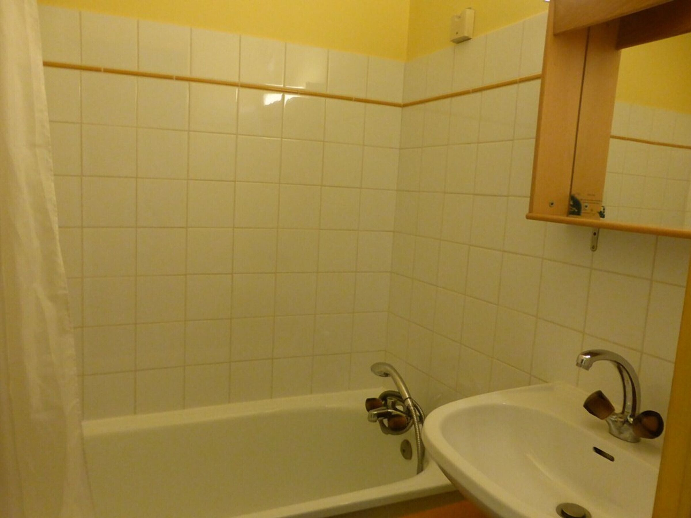 A bathroom with a bathtub, a sink, and a mirror.