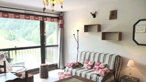 A cozy living room with a striped sofa, a wooden coffee table, and a view of a forest through the window.