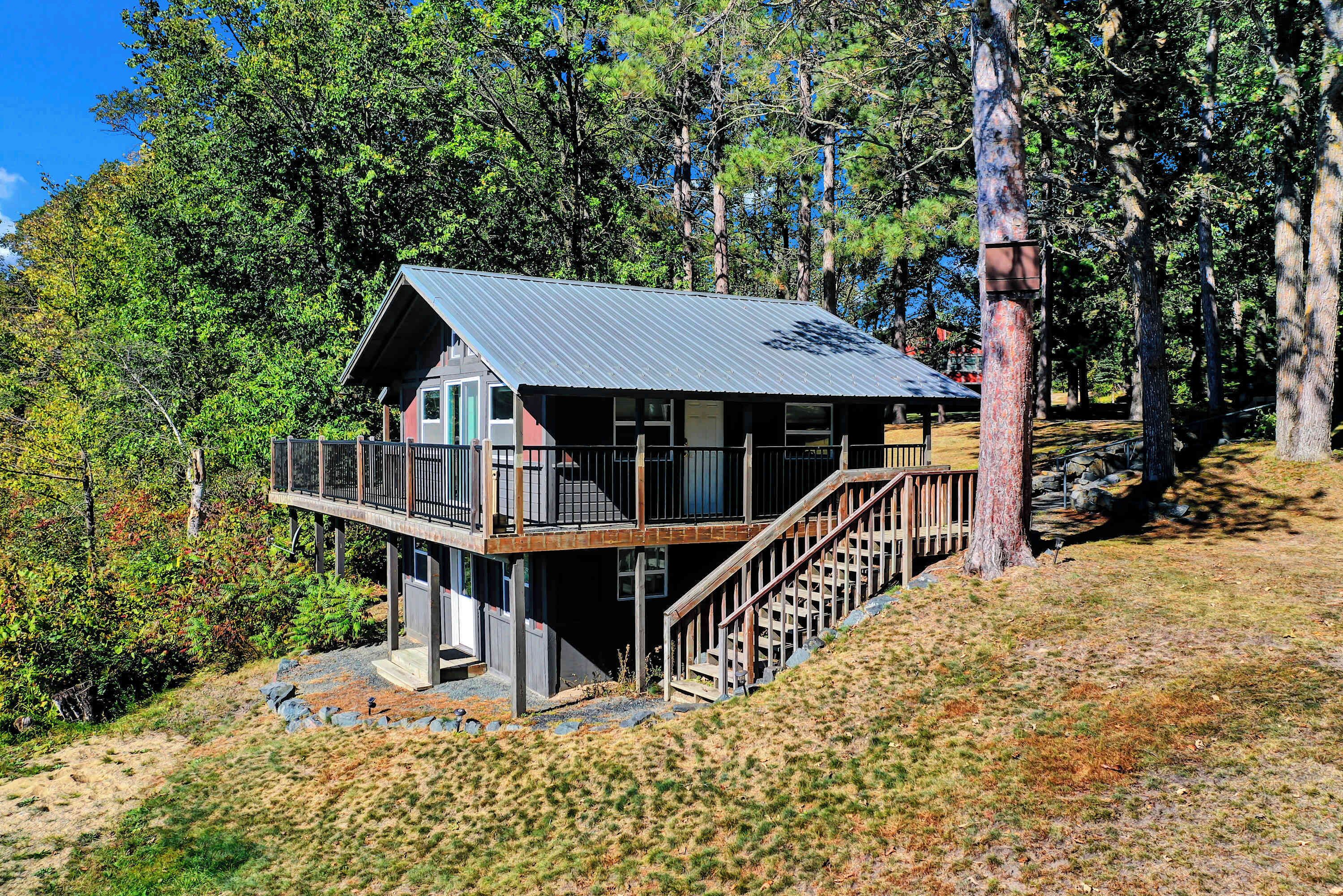 Een chalet met een metalen dak, een terras en een trap naar de ingang.