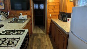 Una cocina compacta con armarios de madera, un lavamanos, una hornilla, un microondas y un refrigerador.
