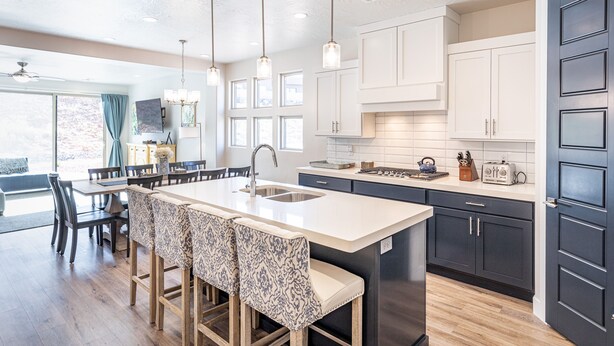 A modern kitchen with a large island, pendant lights, and dark cabinetry. - Sleeps 16 - Private Hot Tub, Fire Pit & Poolside (St. George)