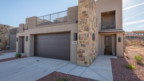 A modern two-story house with a stone facade, a garage, and a balcony with outdoor furniture. - Sleeps 16 - Private Hot Tub, Fire Pit & Poolside (St. George)