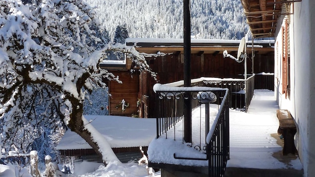 A wooden building with a snow-covered balcony and a mountain backdrop.