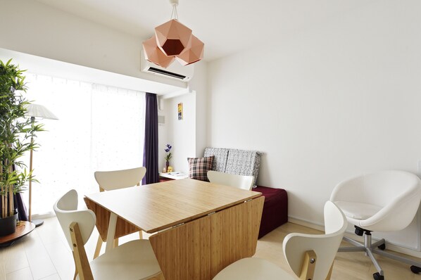 A modern dining area with a wooden table, white chairs, and a unique geometric pendant light. - Namba 2 bedroom apartment! 1min to Nippombashi (大阪市)