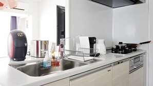 Una cocina moderna con un lavamanos de acero inoxidable, una cafetera, un tostador y un hervidor.