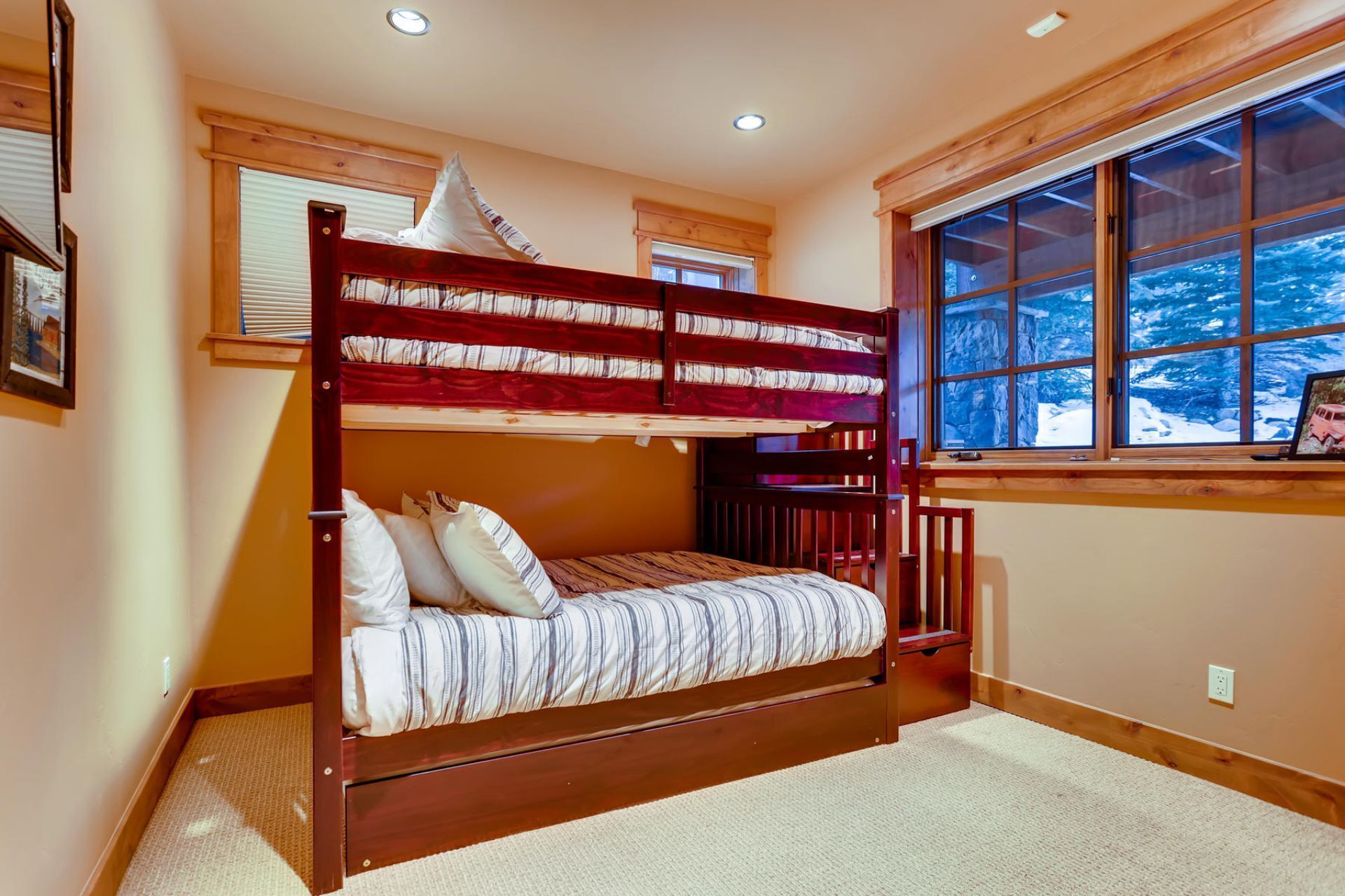 A bunk bed room with a window view of a snowy landscape.