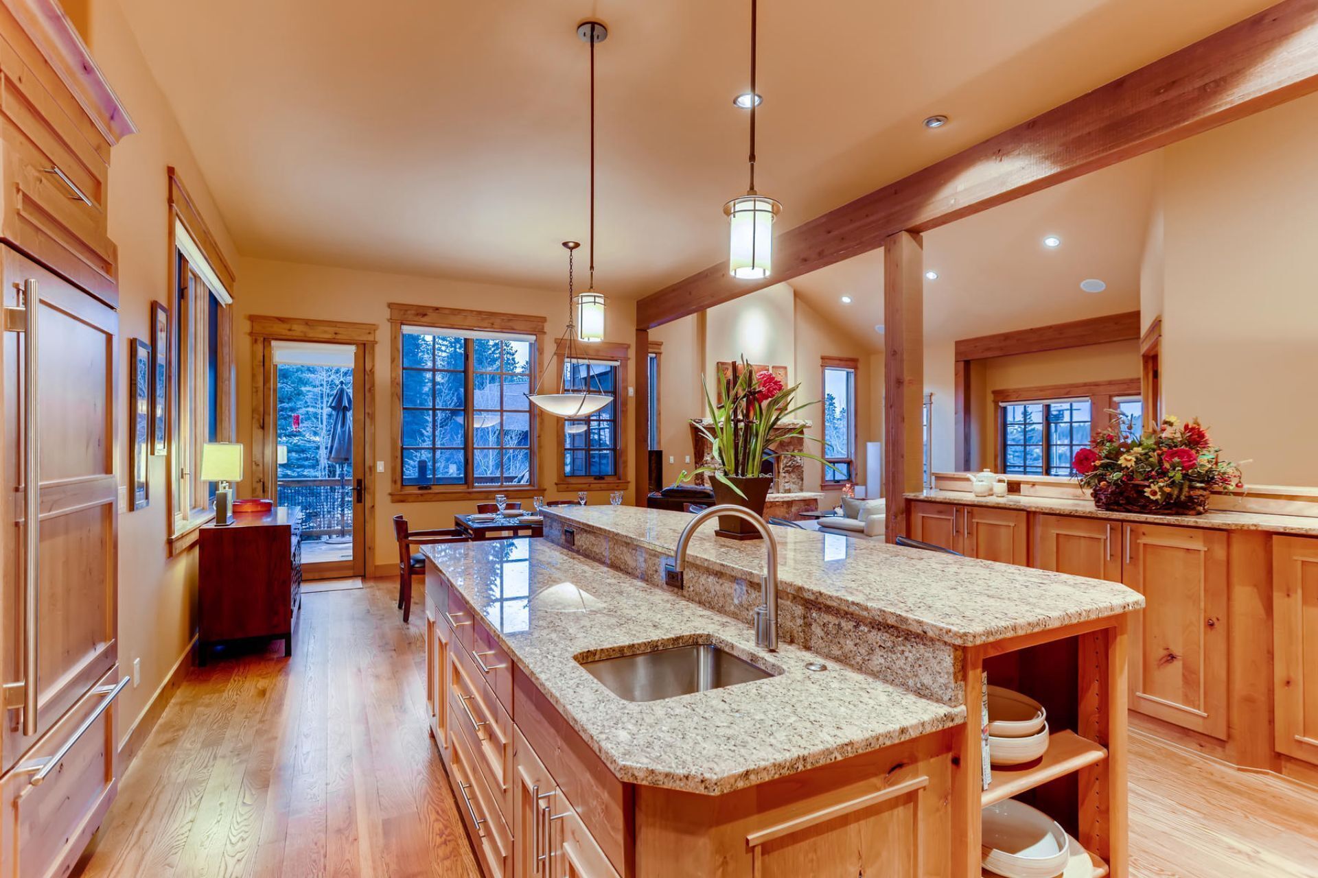 A spacious kitchen with granite countertops, wooden cabinets, and a large island with a sink.