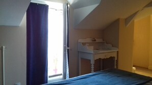 Une chambre à coucher avec un lit, une table de chevet et une fenêtre avec des rideaux.