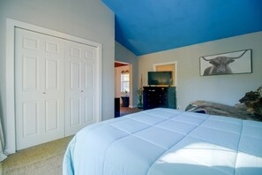 Un dormitorio con una cama grande, un televisor y una puerta.