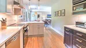 A modern kitchen with a central island, stainless steel appliances, and pendant lighting. - Charming Farmhouse Hot Tub Three Acres (Candler)