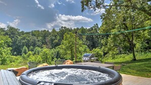 A hot tub with a wooden exterior, surrounded by a patio area with a grill and seating. - Charming Farmhouse Hot Tub Three Acres (Candler)