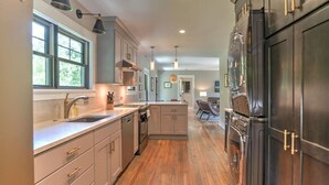 A modern kitchen with wooden flooring, stainless steel appliances, and a central island. - Charming Farmhouse Hot Tub Three Acres (Candler)