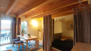 A cozy room with a wooden ceiling, a bed, a table with chairs, and a TV. - Pension on the Elbe bridge - Apartment New Venice (Berlin)