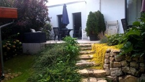 A stone pathway leading to a patio area with outdoor furniture and a potted plant. - Pension on the Elbe bridge - Apartment New Venice (Berlin)