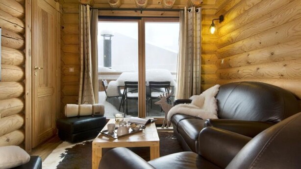 A log cabin interior with a leather sofa, a wooden coffee table, and a dining area with a table and chairs. - Chalet Ana: THE LLOSE (Les Angles)