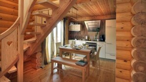 Ein Holzhäuschen im Inneren mit einer Wendeltreppe, einem Essbereich und einer Küche.