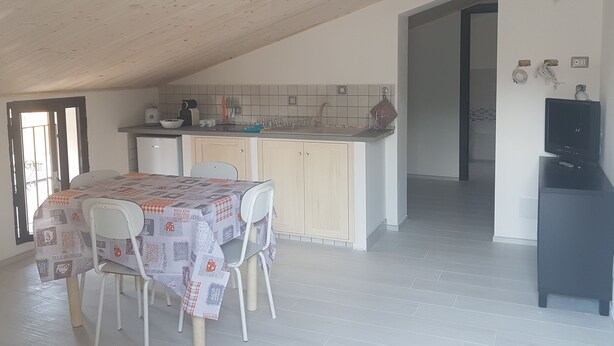 Una cocina compacta con comedor, que incluye una mesa con sillas, un refrigerador y un lavamanos.