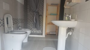 Un baño moderno con dos inodoros, un lavamanos y una zona de ducha.