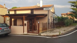 Una casa de dos pisos con fachada marrón, una chimenea visible y un letrero que dice 'via raffaello'.
