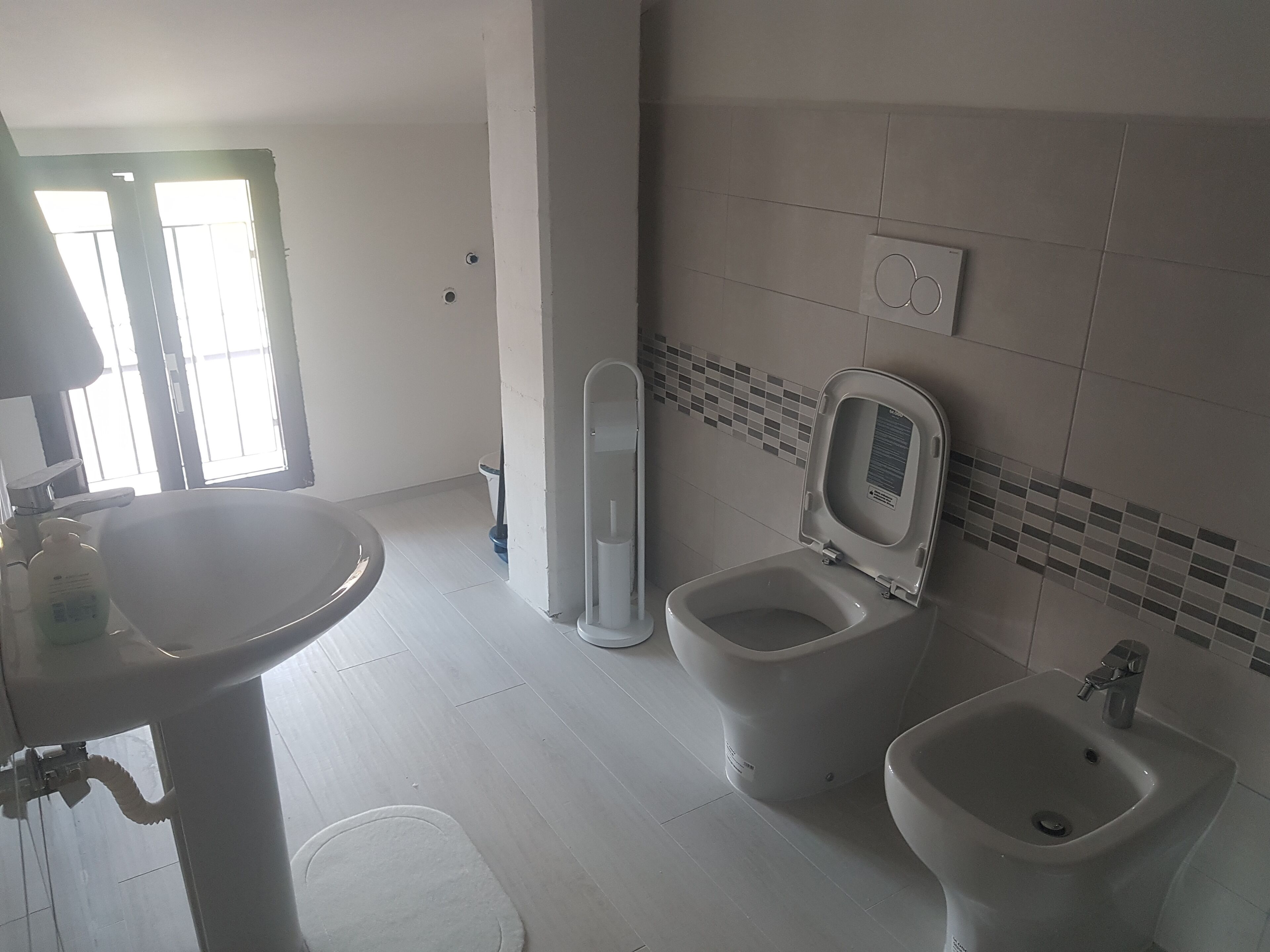 A bathroom with a sink, toilet, bidet, and a tiled backsplash.