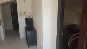 Un pasillo con un mueble negro para televisor, una puerta y un enchufe de pared.