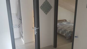 Ein Zimmer mit einem Bett, einem Kleiderschrank und einer Tür zu einem anderen Raum.