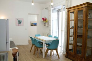 A dining area with a wooden table and teal chairs, a cabinet with glass doors, and a wall-mounted flower arrangement.