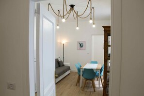 A dining area with a table and chairs, a sofa, and a chandelier.