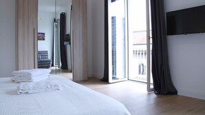 A modern bedroom with a large bed, a wardrobe, a sliding glass door to the balcony, and a flat-screen TV mounted on the wall. - Fabiana house, apartment in the historic center for short or long periods (Napoli)