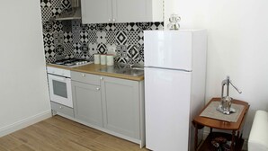 A compact kitchen with a gas stove, sink, and white refrigerator. - Fabiana house, apartment in the historic center for short or long periods (Napoli)