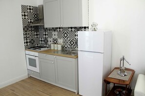 A compact kitchen with a gas stove, sink, and white refrigerator.
