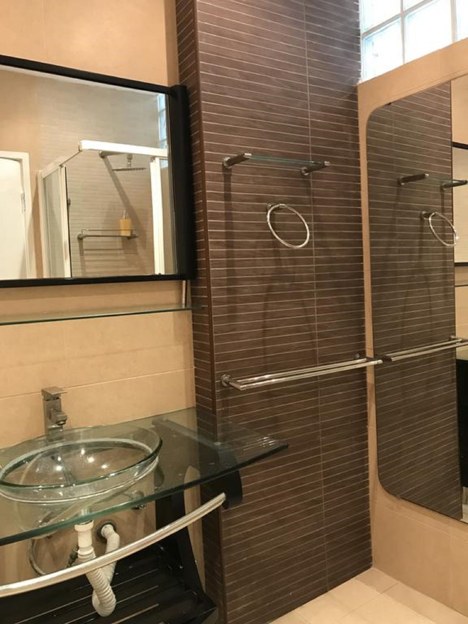 A modern bathroom with a glass sink, a large mirror, and a walk-in shower with a glass door.