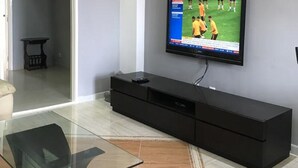 Un saló modern amb un televisor de pantalla plana muntat a la paret, una taula de centre de vidre i un moble de televisió fosc.
