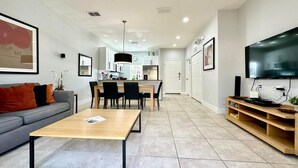 A modern living room with a sofa, coffee table, TV stand, and dining area. - A Dream Villa next to Disney. (Kissimmee)