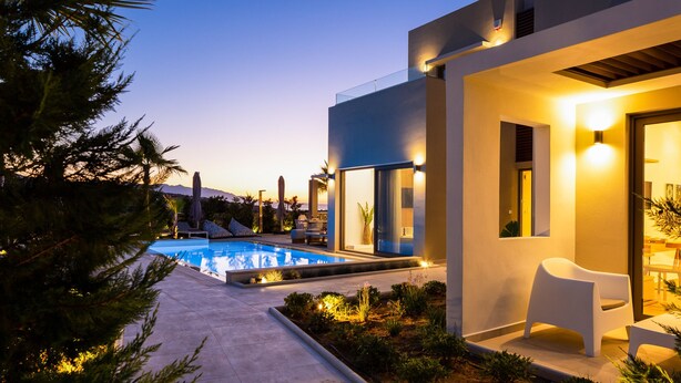 Uma casa moderna com piscina, área de estar externa e entrada bem iluminada.