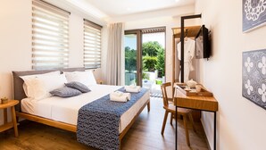 Quarto de hotel moderno com uma cama grande, uma escrivaninha e varanda com vista para o verde.