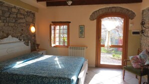 A bedroom with a bed, a radiator, a window, and a door leading to an outdoor area.