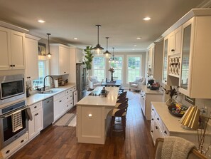 A spacious kitchen with white cabinetry, a central island, and a dining area with a white chair. - Contemporary Country Charm in Franklin TN! Minutes from Cool Springs & Nashville (Franklin)