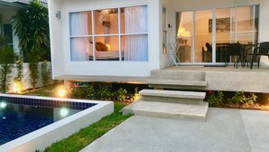 Ein modernes Haus mit Swimmingpool, Terrasse und Gartenmöbeln sowie ein gepflegter Garten.
