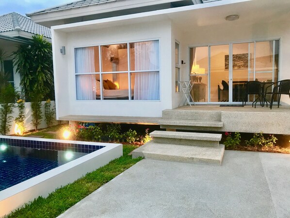 A modern house with a swimming pool, a patio with outdoor furniture, and a well-maintained garden.