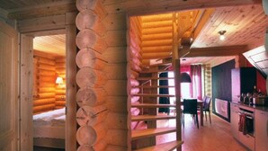 Interior de una cabaña de madera con una escalera de madera, un comedor y una cocina.