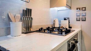 A modern kitchen with a gas stove, a coffee machine, and a set of knives on the counter. - Comfy Bayswater Apartment (London)
