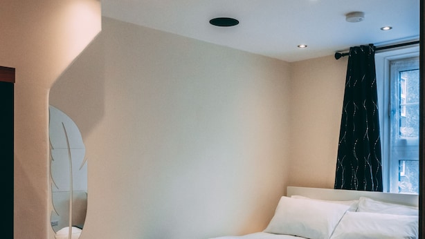 Ein modernes Schlafzimmer mit Bett, Holzboden und Einbaustrahler.